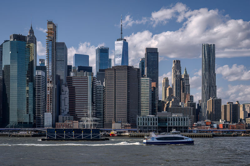Soubor:A Brooklyn-bound New York Ferry passes a barge on the East River with the view of Lower Manhattan in the background-DRFlickr.jpg
