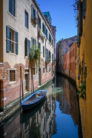 Blue boat with reflections in a canal near Campo San Polo in Venice.